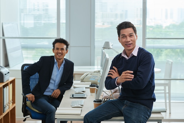 Male colleagues in the spacious office looking at camera cheerfully