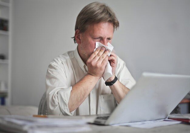 Male at the computer blows his nose