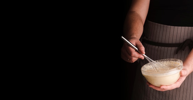 Free photo male cook holding bowl with and whisking mixture