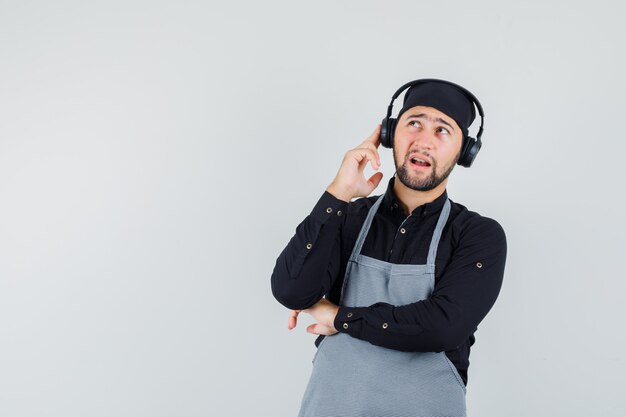 Male cook looking up with headphones in shirt, apron front view.