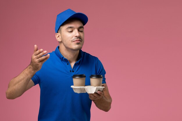 Курьер-мужчина в синей форме доставляет кофейные чашки, пахнущие розовым, служба доставки униформы