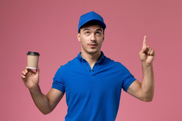 male courier in blue uniform holding delivery coffee cup on pink, uniform service job delivery