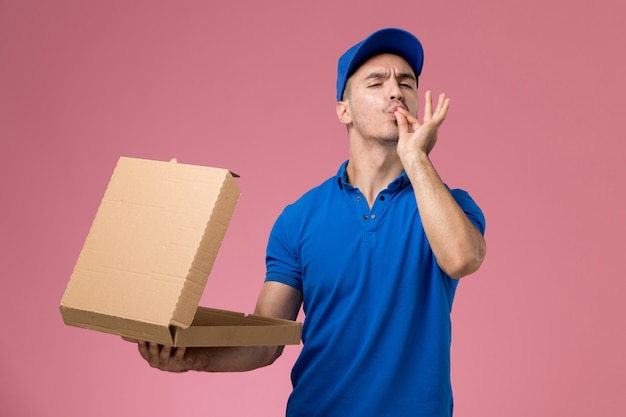 male courier in blue uniform holding delivery food box on pink, uniform service delivery