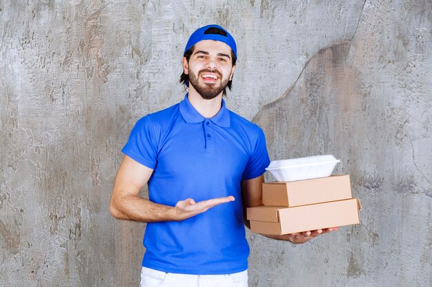 無料写真 段ボールとプラスチックの箱を運ぶ青い制服を着た男性の宅配便。