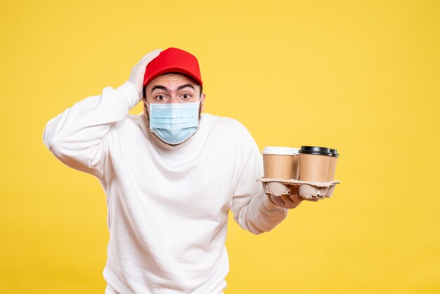 male courier in mask holding coffee on yellow