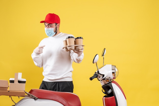 male courier in mask holding coffee on yellow