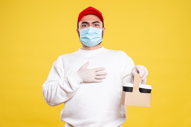 薄黄色の配達用コーヒーを保持しているマスクの男性宅配便