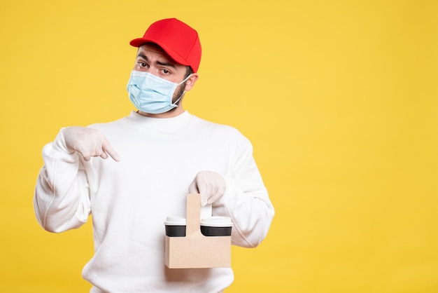 Free photo male courier in mask holding delivery coffee on yellow