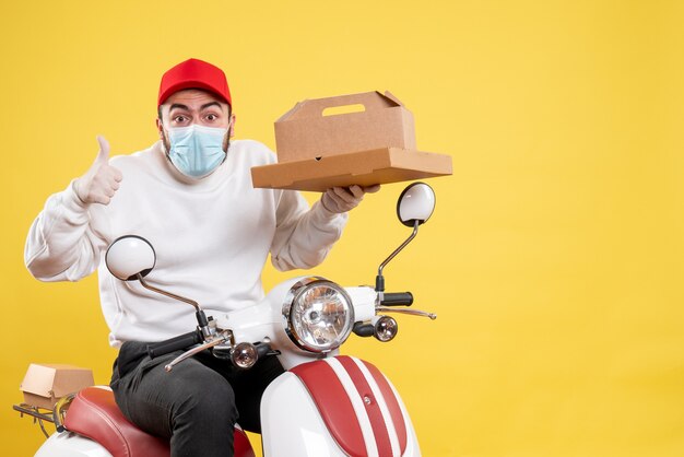 male courier in mask holding delivery food on yellow