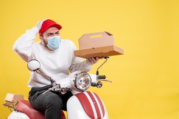 male courier in mask holding delivery food on yellow