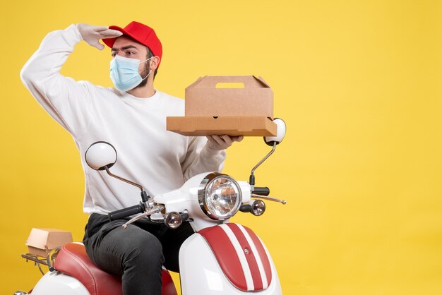 male courier in mask holding delivery food on yellow