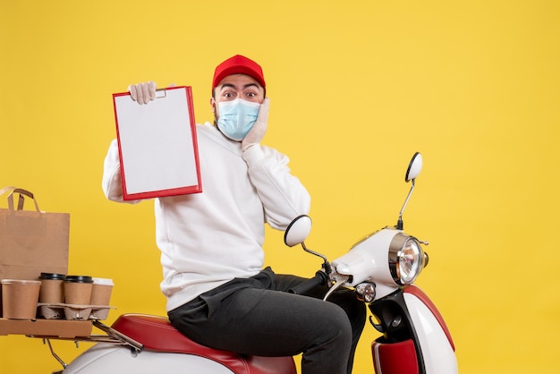 Male courier in mask holding file note on yellow