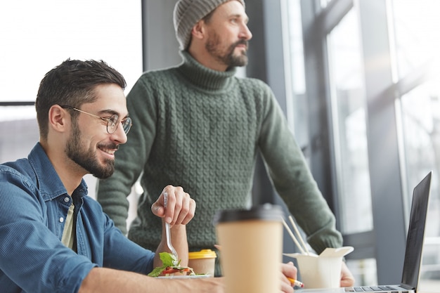 Male coworkers in office with lunch