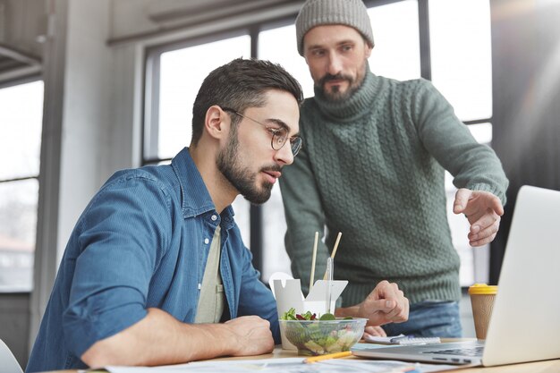 Male coworkers in office with lunch