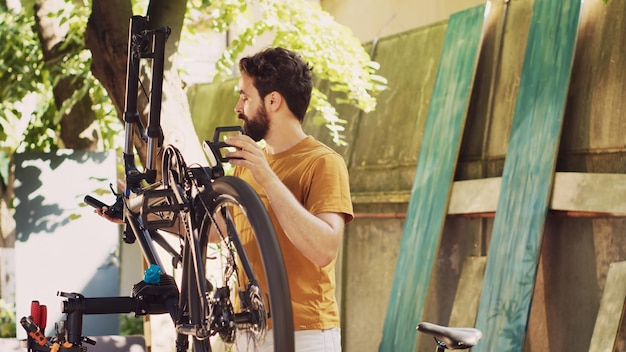 男のサイクリストが庭で自転車のギアを修理している