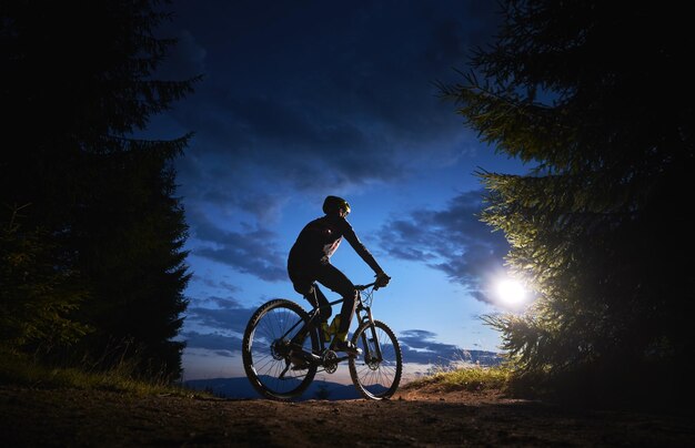 美しい夜空の下で自転車に座っている男性サイクリスト