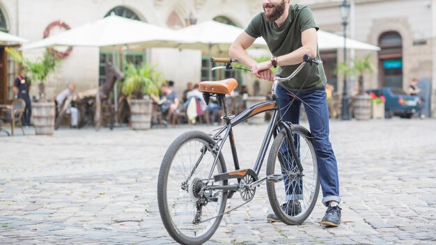 Male cyclist with bicycle standing on city street