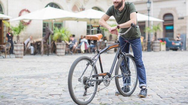 Мужской велосипедист с велосипедом, стоящим на городской улице
