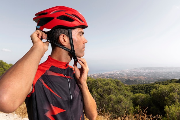 Free photo male cyclist with bike and helmet outdoors in nature