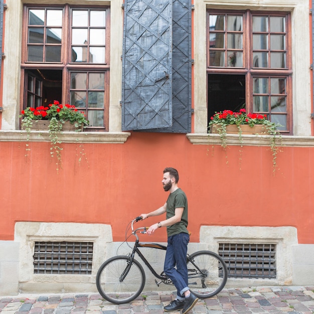 Male cyclist with his bicycle in front of building