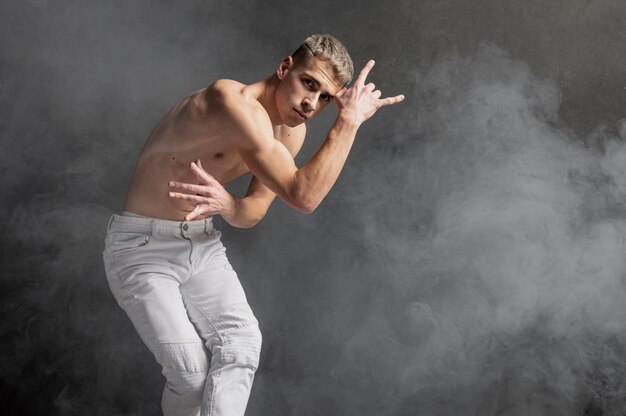 Male dancer posing in jeans with fog and copy space