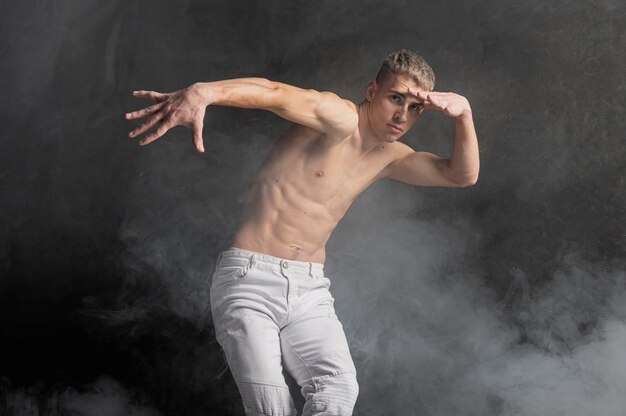 Мужской танцор позирует в дыму с джинсами