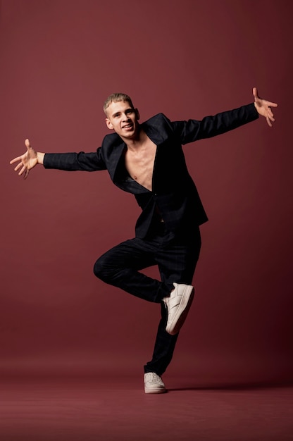 Male dancer in sneakers and suit without shirt busing a move