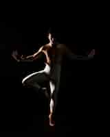 Free photo male dancer standing against black background with extended hands