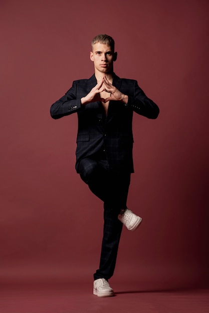 Male dancer in suit and sneakers making yoga pose