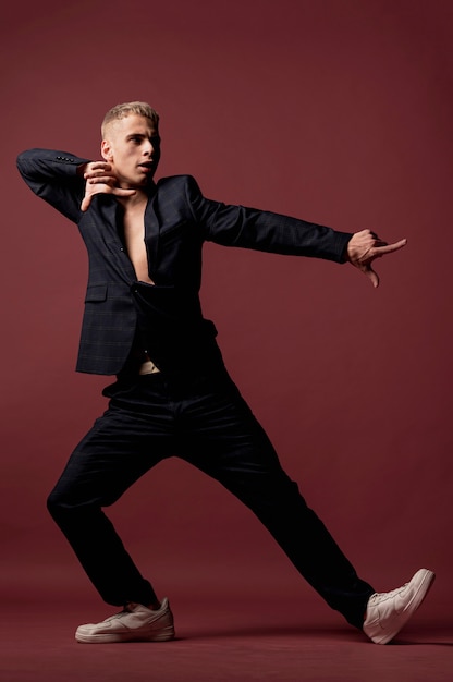 Male dancer in suit and sneakers posing while pointing fingers