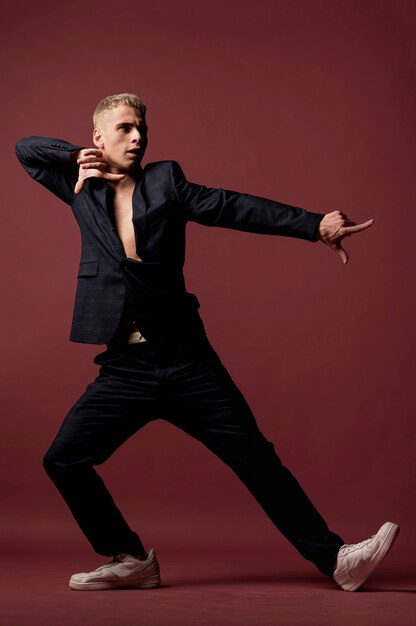 Male dancer in suit and sneakers posing while pointing fingers