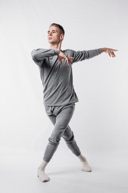 Male dancer in tracksuit and socks giving ballet pose