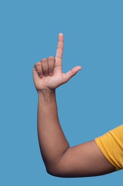 Male demonstrating a finger gun gesture isolated over the blue background