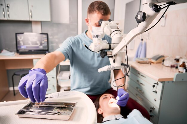 치과 절차 중 치과 탐색기를 잡는 남성 치과 의사