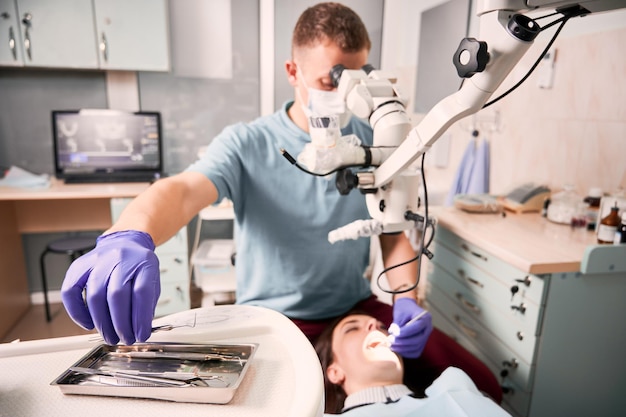 Foto gratuita dentista maschio che afferra l'esploratore dentale durante la procedura dentale