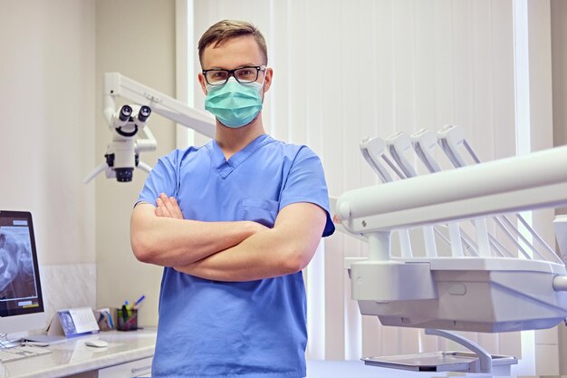 배경에 의료 장비가 있는 방에 있는 남성 치과의사.