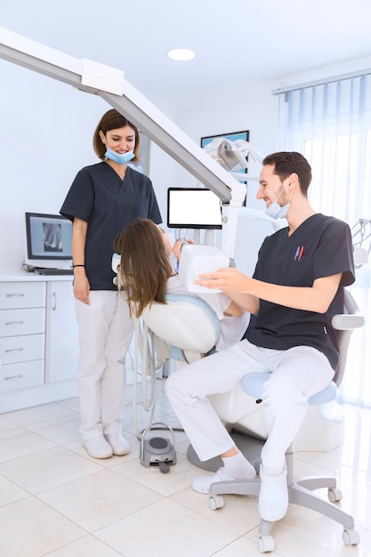 Foto gratuita dentista maschio che si siede sulla sedia che esamina i denti del paziente femminile con la macchina dei raggi x