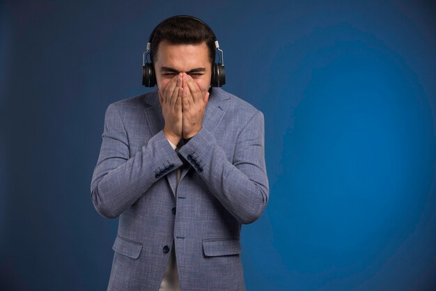 Male dj in grey suit listening to headphones . 