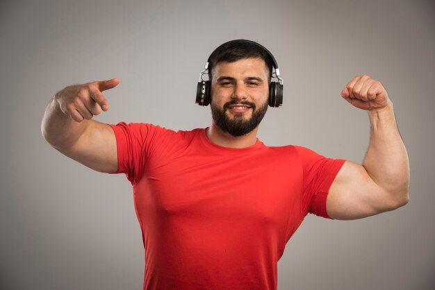 Male dj in red shirt wearing headphones and dancing. 