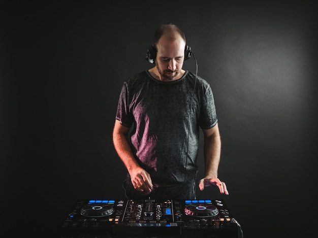 Male DJ working under the lights against dark