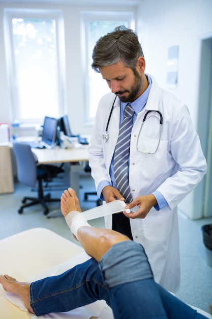 Male doctor bandaging foot of female patient