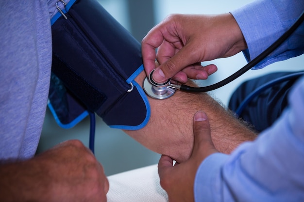 Male doctor checking blood pressure of patient