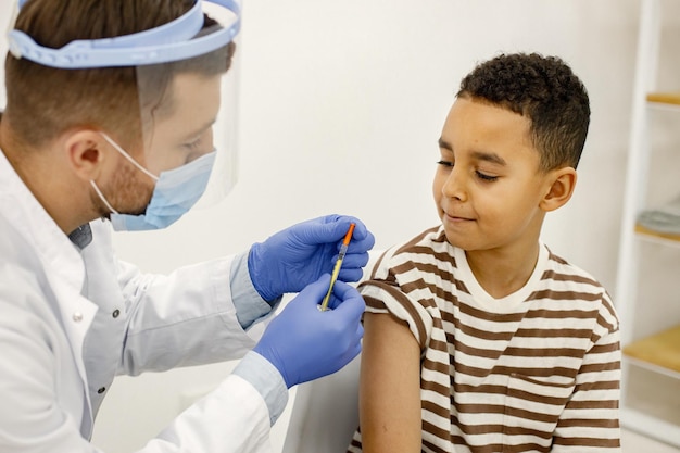 Male doctor doing a vaccination to a multiracional boy