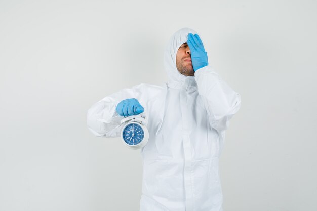 Free photo male doctor holding alarm clock in protective suit