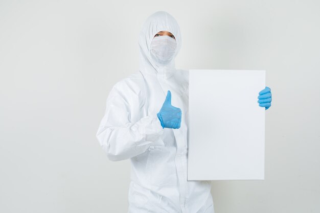 Male doctor holding blank canvas, showing thumb p in protective suit