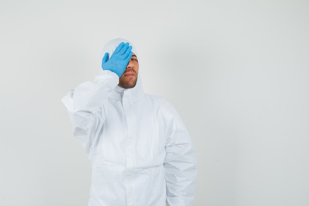 Free photo male doctor holding hand on on eye in protective suit