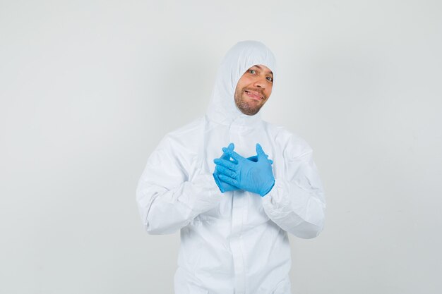 Male doctor holding hands on chest in protective suit