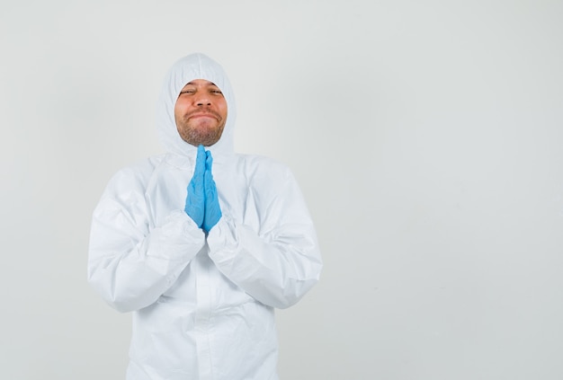 Male doctor holding hands in praying gesture in protective suit