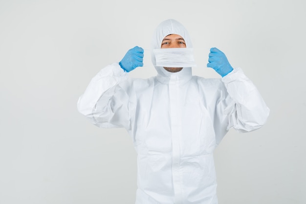 Free photo male doctor holding medical mask over face in protective suit