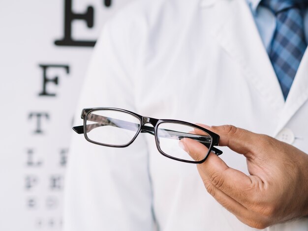 Male doctor holding a pair of eyeglasses in his hands
